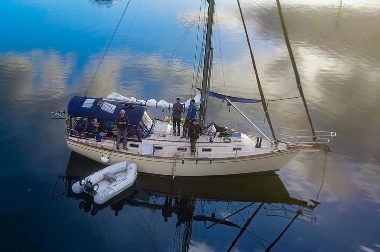 Island Packet Cutter 1997 Island Packet Cutter sailboat with crew, calm waters, and a small dinghy nearby.