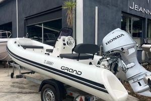 Grand S420 2024 Grand S420 boat with Honda engine on trailer outside dealership.