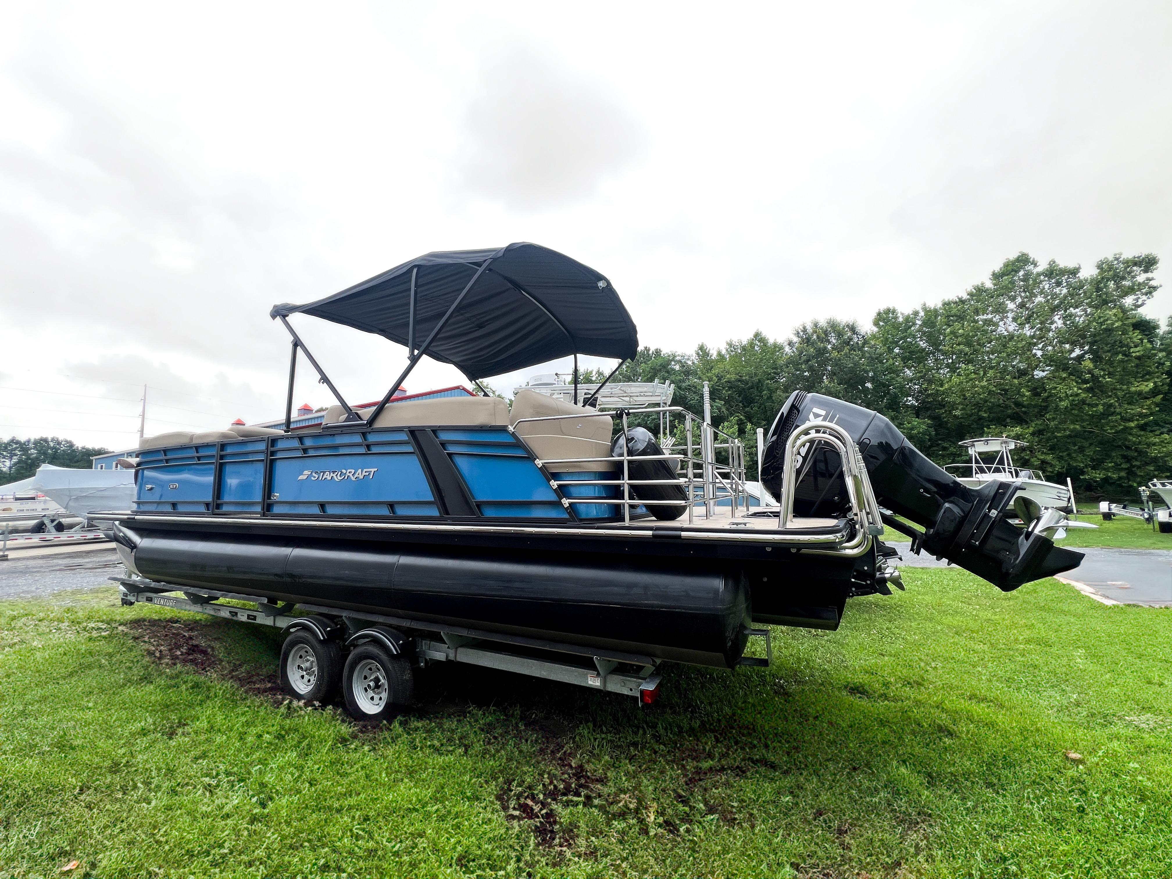 Starcraft SLS 5 Q 2024 Starcraft SLS 5 Q pontoon boat on trailer, blue and black design, parked on grass.