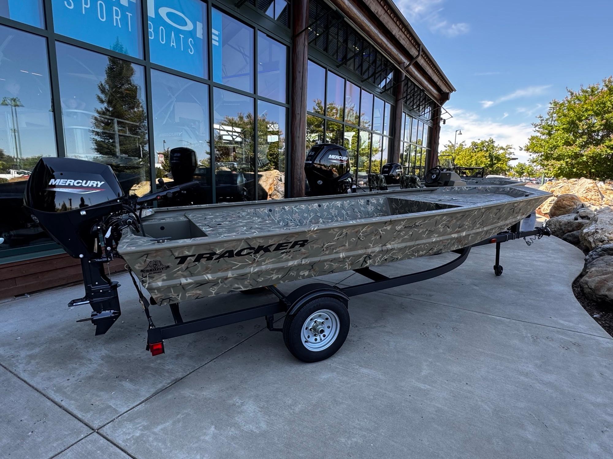 Tracker Grizzly 1648 Jon 2025 Tracker Grizzly 1648 Jon boat with Mercury engine, displayed outside a showroom.