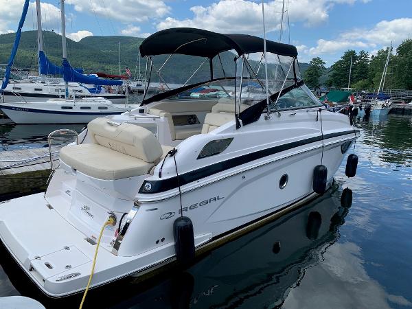 Regal 28 Express 2018 Regal 28 Express boat docked at marina, surrounded by other boats and scenic mountains.