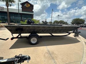 Tracker Grizzly 1860 Utility 2025 Tracker GRIZZLY 1860 Utility boat on trailer, parked outside a store under cloudy sky.