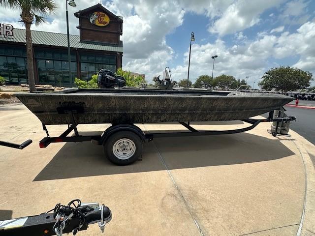 Tracker GRIZZLY 1860 Utility 2025 Tracker GRIZZLY 1860 Utility boat on trailer, parked outside a store under cloudy sky.