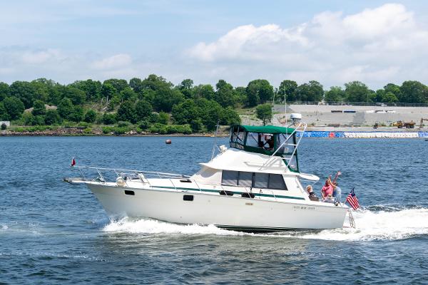 Silverton 37 Convertible 1981 Silverton 37 Convertible boat cruising on a sunny day with passengers waving.