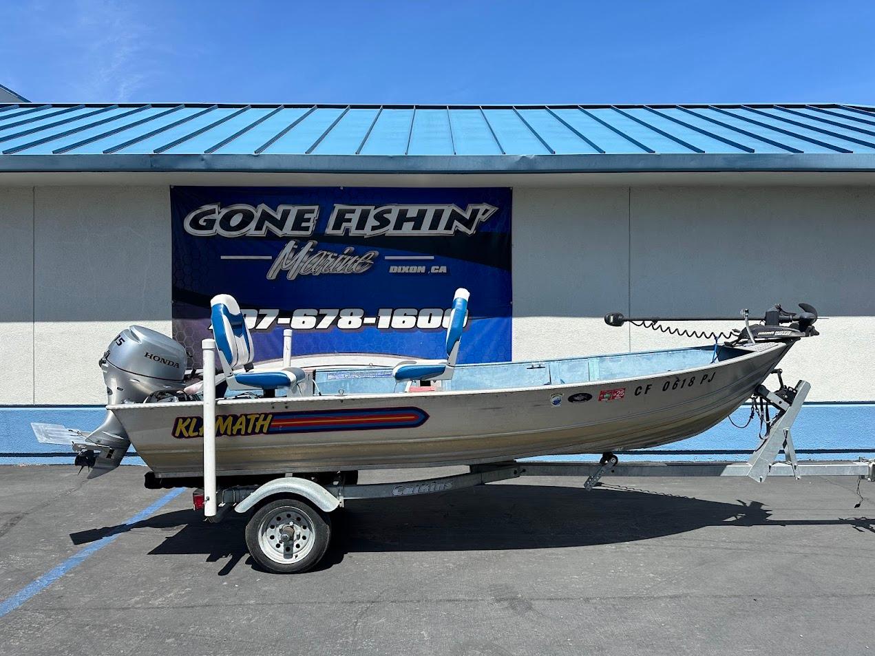 Klamath 14 DLX 1998 Klamath 14 DLX boat on trailer, parked outside "Gone Fishin'" store.
