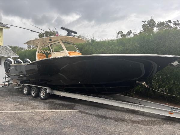Scout 350 LXF 2014 Scout 350 LXF boat on trailer, parked outdoors under cloudy sky.