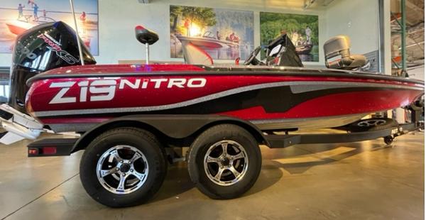 Nitro Z19 2025 Nitro Z19 boat in showroom, red and black design, dual axle trailer.