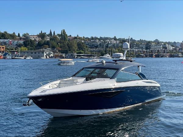Cobalt A36 2020 Cobalt A36 boat cruising on a scenic lake with cityscape background.