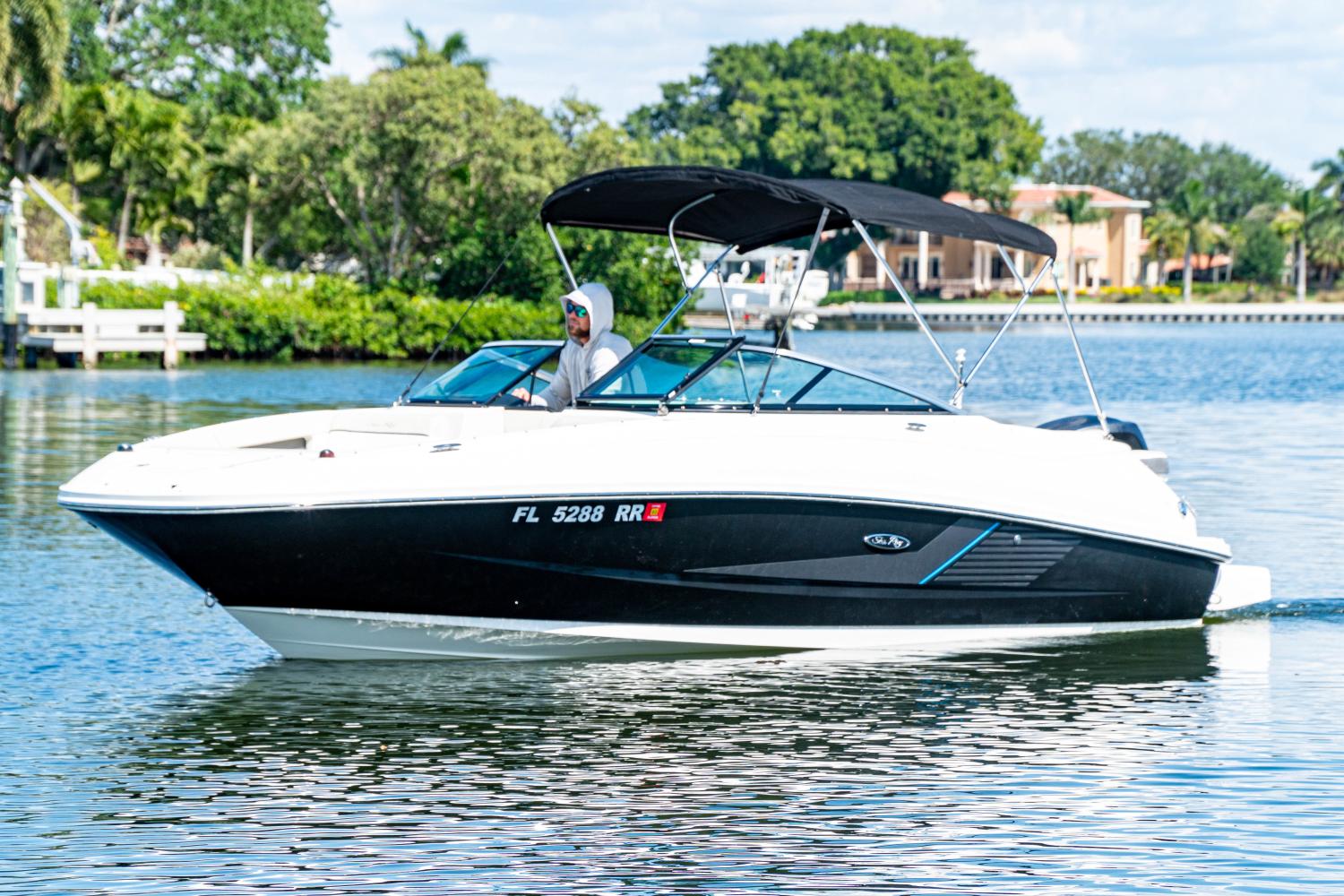 Sea Ray 240 Sundeck Outboard 2014 Sea Ray 240 Sundeck Outboard cruising on a sunny day, with lush greenery in the background.