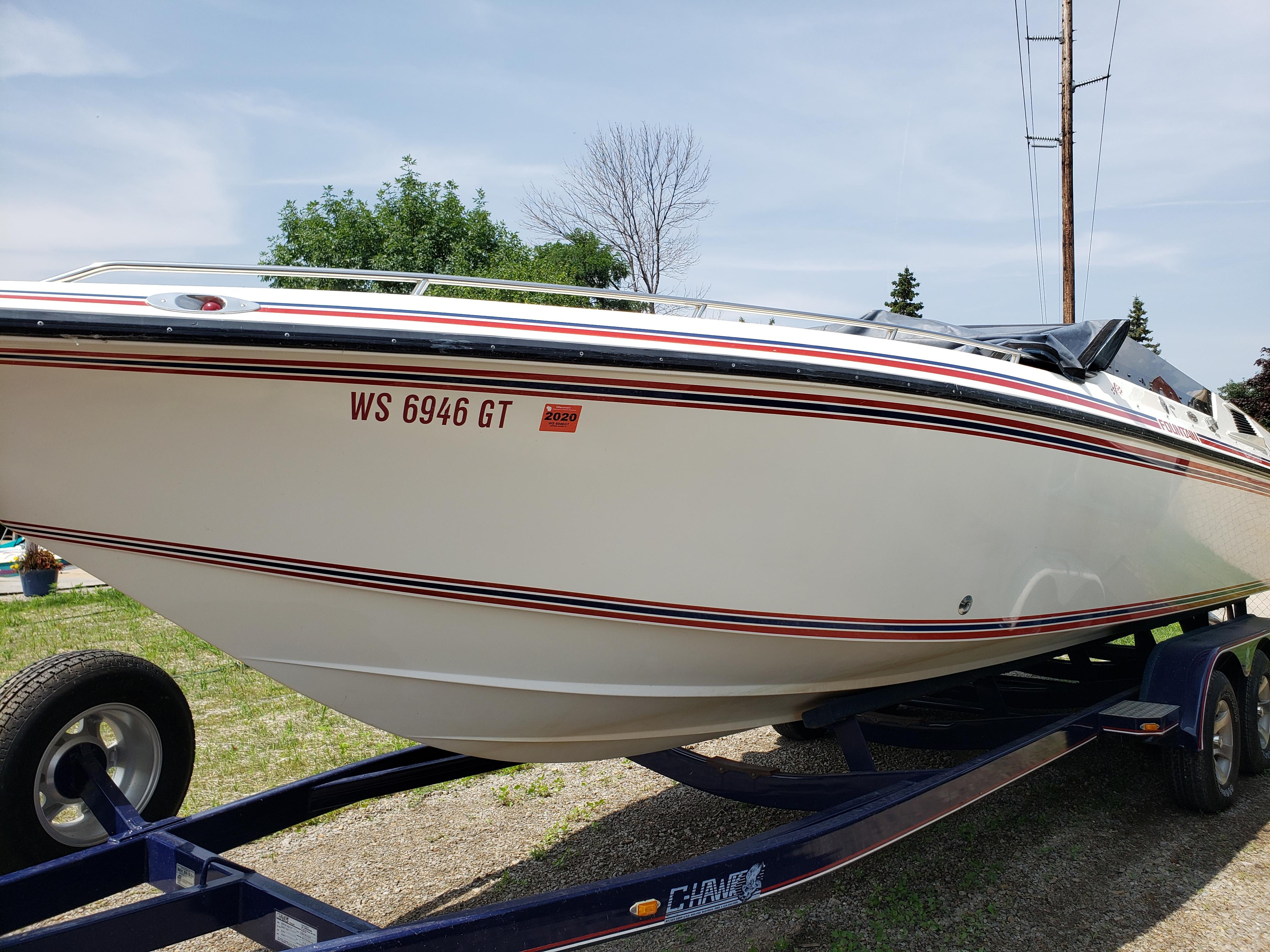 Fountain 27 Fever 1990 Fountain 27 Fever speedboat on trailer, white with red stripes, parked outdoors.