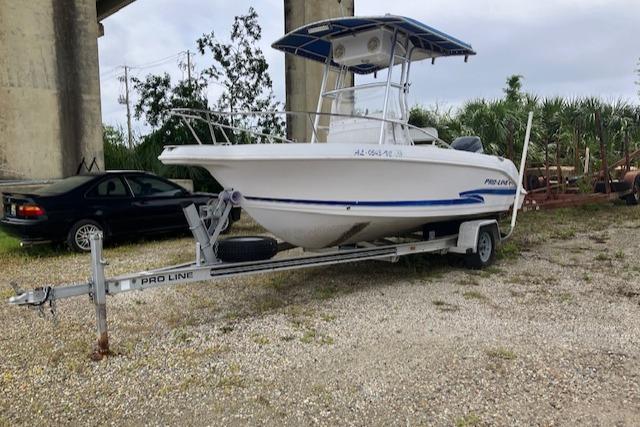 Pro-Line 19 SPORT 2002 Pro-Line 19 SPORT boat on trailer, parked outdoors near a car and greenery.