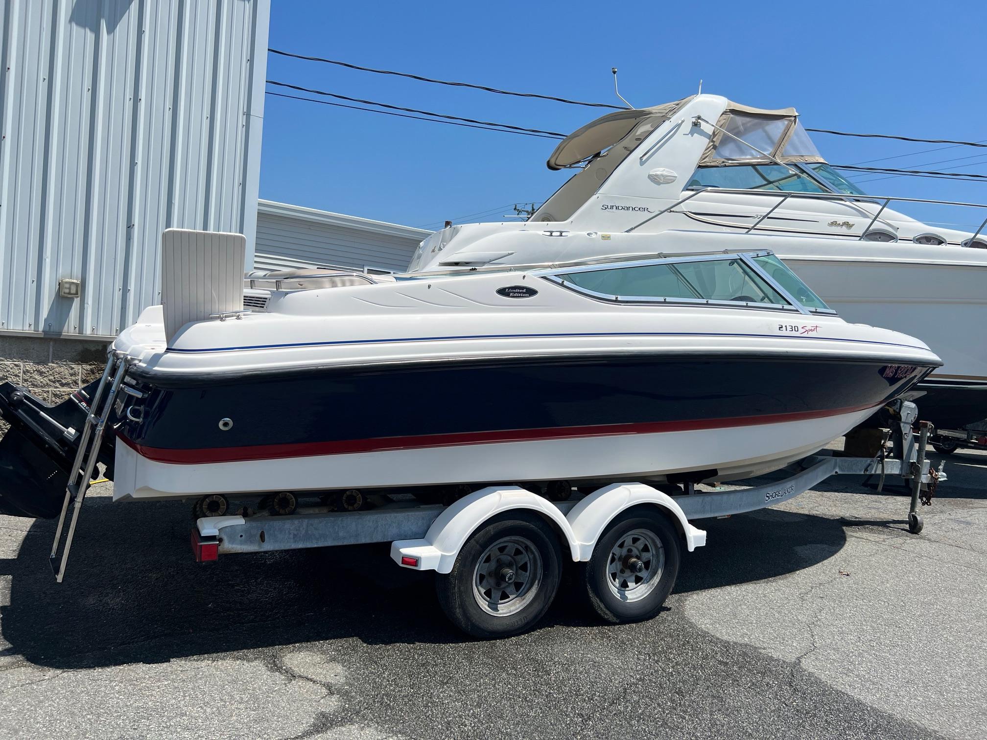 Chaparral Sunesta 2000 Chaparral Sunesta boat on trailer, parked outdoors near a metal building.