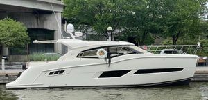 Carver C43 Coupe 2016 Carver C43 Coupe yacht docked by a waterfront with lush greenery.