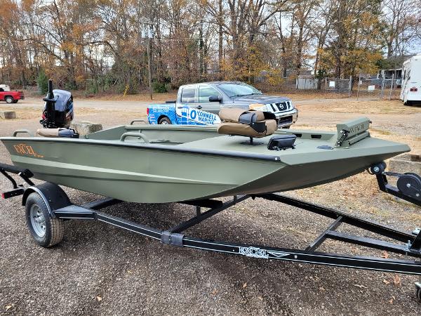 Excel Eclipse 2025 Excel Eclipse boat on trailer, parked outdoors with trees in background.