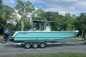 Contender 32 ST 2011 Contender 32 ST boat on trailer, parked outdoors with trees in background.