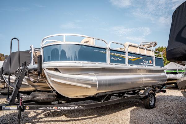 Sun Tracker BASS BUGGY 18 2025 Sun Tracker BASS BUGGY 18 pontoon boat on trailer, parked outdoors.