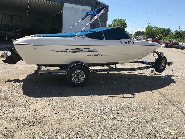 Stingray 195 RX 2012 Stingray 195 RX boat on trailer, parked outdoors, with blue canopy.