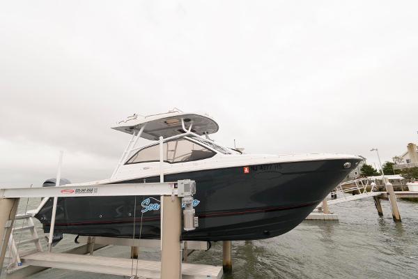 Solara S-250 DC 2023 Solara S-250 DC boat docked on a lift, overcast sky.