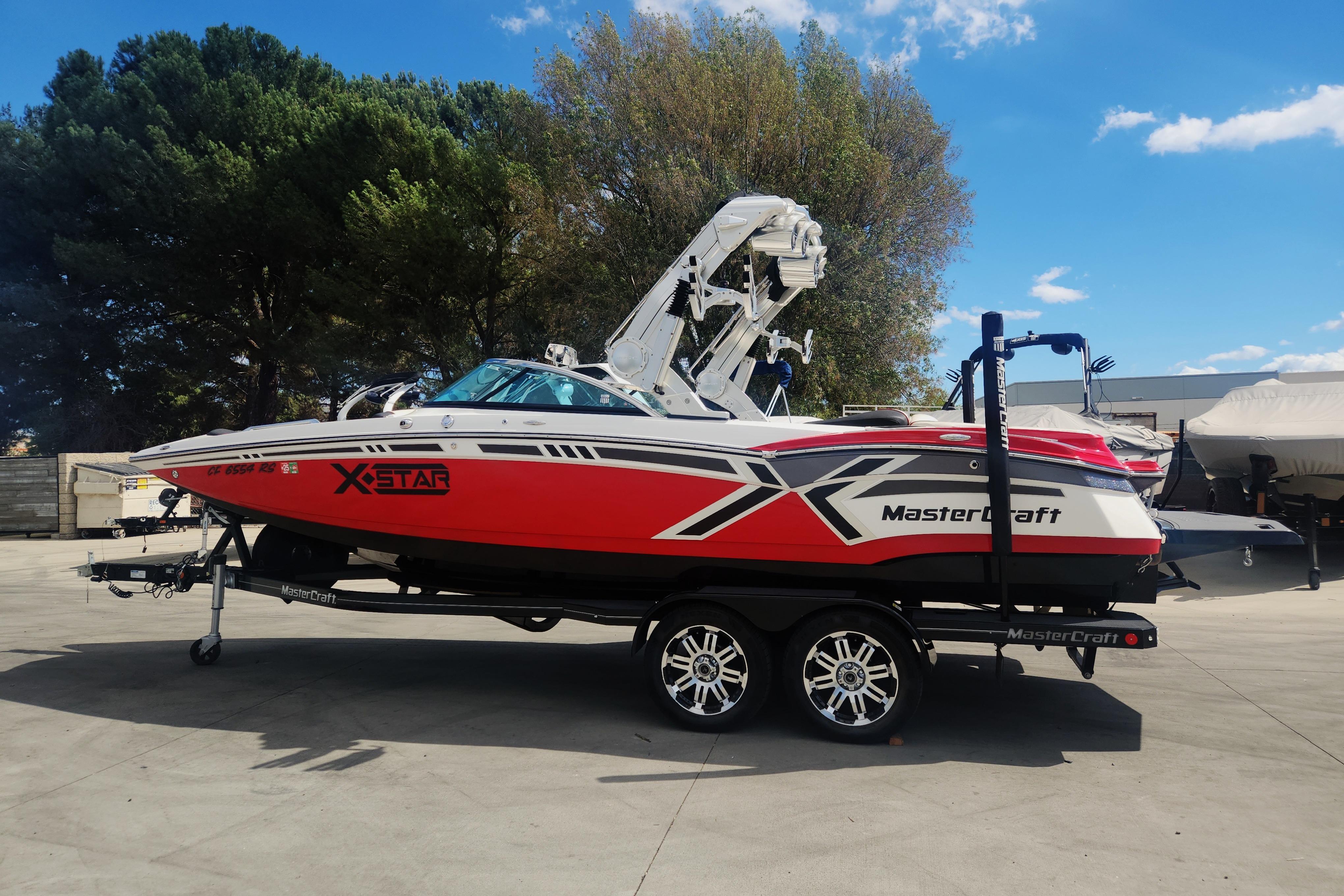 MasterCraft XStar 2013 MasterCraft XStar boat on trailer, red and white design, parked outdoors.