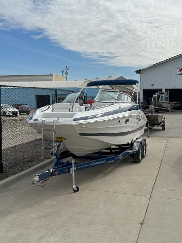 Crownline E235 2025 Crownline E235 boat on trailer, parked outdoors near a building.