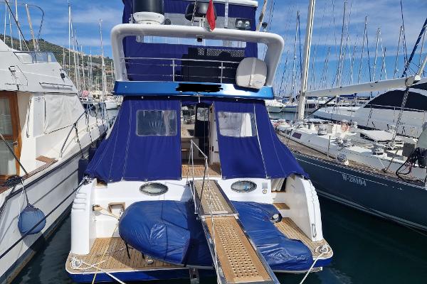 Motor Yacht Lombardi 48 Fly 1998 Lombardi 48 Fly motor yacht docked at marina, featuring blue covers and wooden deck.