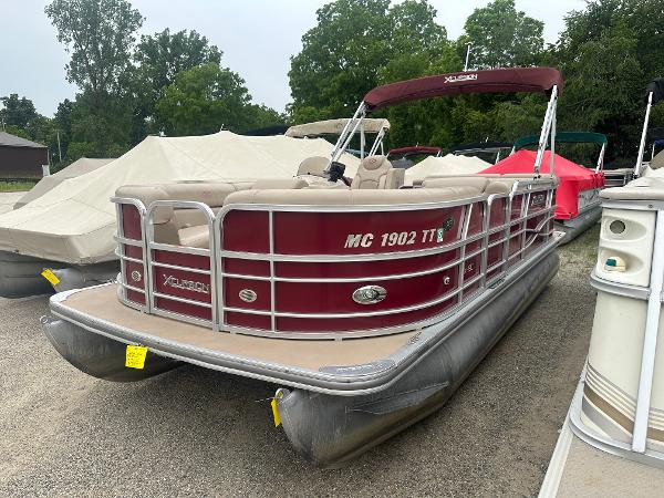 Xcursion X19C 2014 Xcursion X19C pontoon boat with maroon exterior, parked on gravel, surrounded by trees.