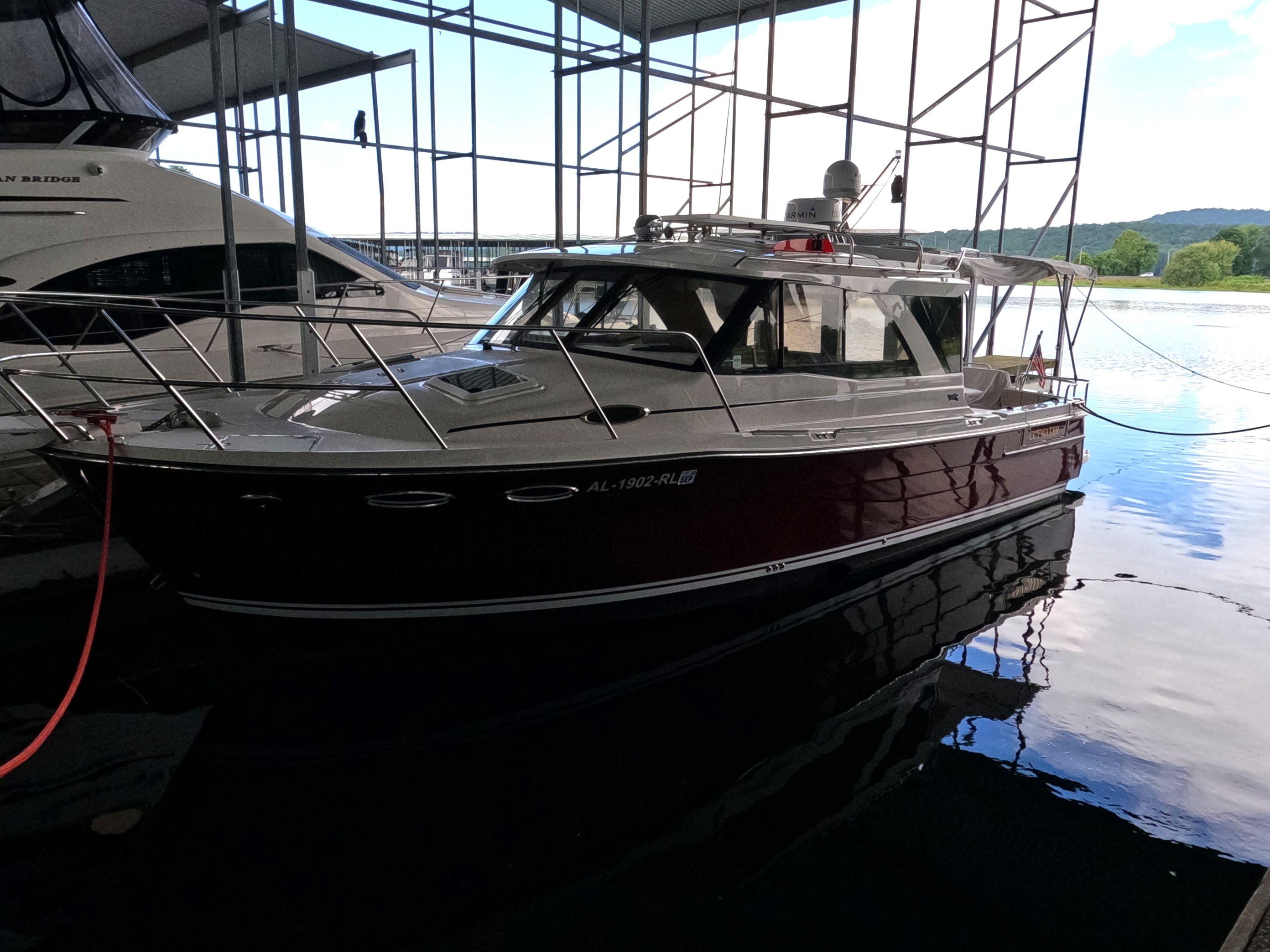 Cutwater C-30 Sedan 2020 Cutwater C-30 Sedan boat docked in a marina under a covered structure.
