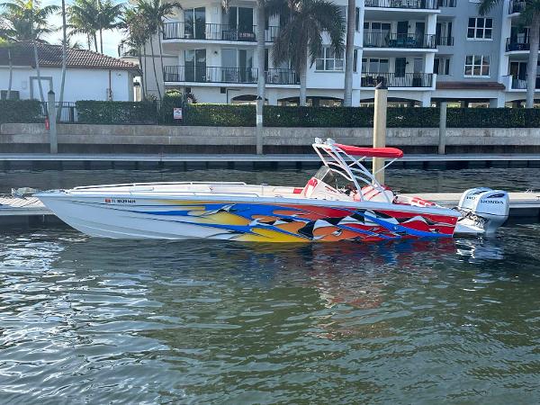 Concept 36 Colorful 2003 Concept 36 boat docked by waterfront apartments, featuring vibrant graphics and Honda outboard engine.