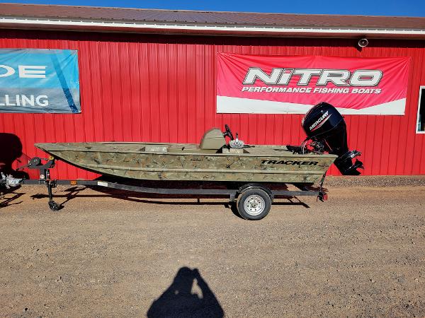 Tracker Grizzly 1648 SC 2024 Tracker Grizzly 1648 SC fishing boat on trailer, parked outside a red building.