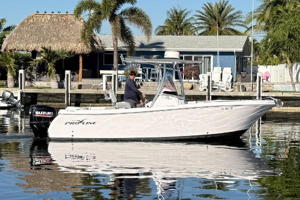 Pro-Line 23 Sport 2019 Pro-Line 23 Sport boat on water near tropical dockside setting.