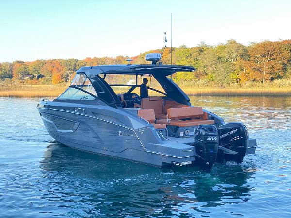 Cruisers Yachts 34 GLS OB 2023 Cruisers Yachts 34 GLS OB on serene water with autumn foliage backdrop.