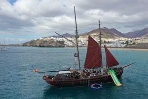 Gulet Pedro Santaña Vintage 1940 custom ship "Pedro Santaña" with red sails and slide, near coastal town.