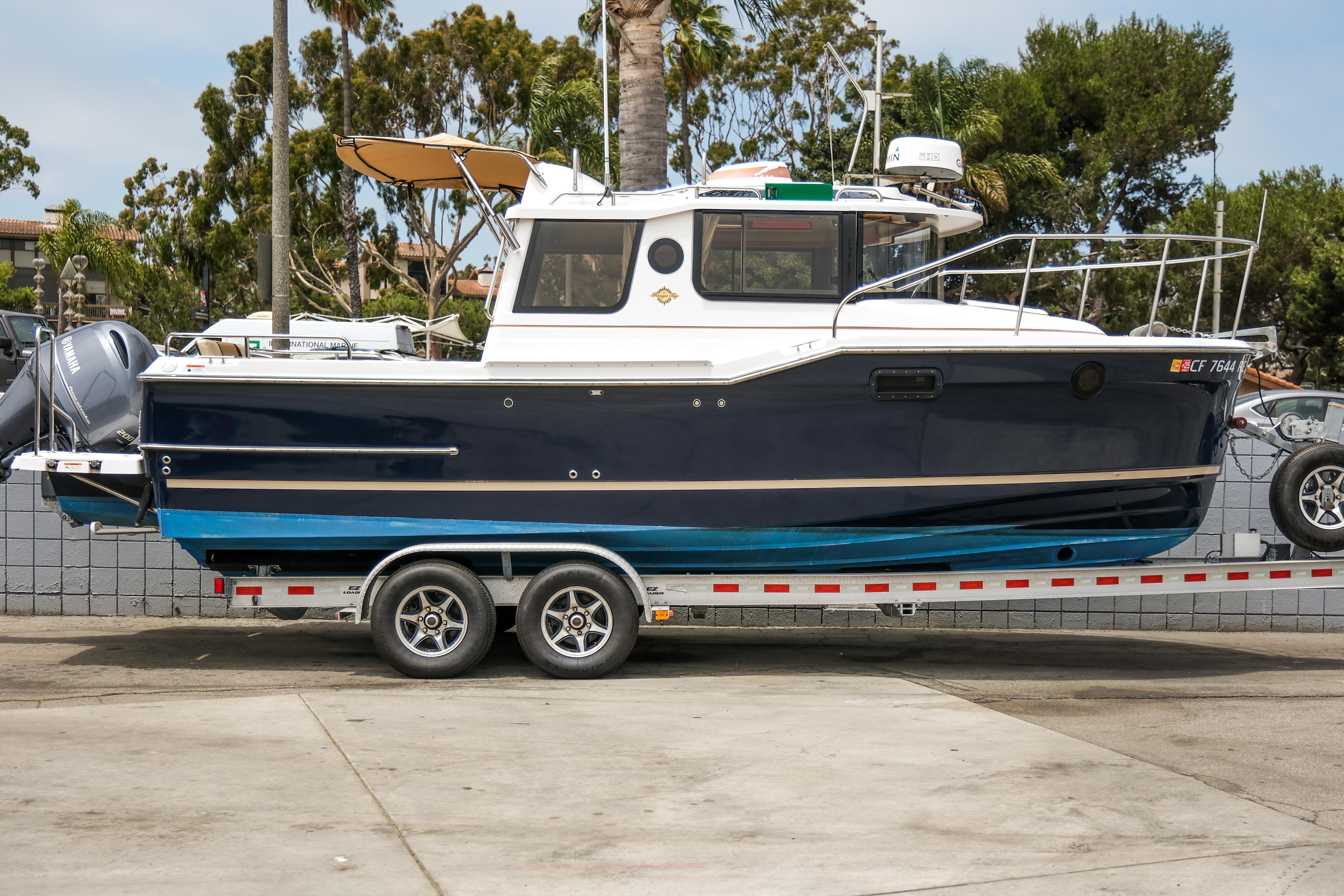 Ranger Tugs R-23 2018 Ranger Tugs R-23 boat on trailer, parked outdoors with trees in background.