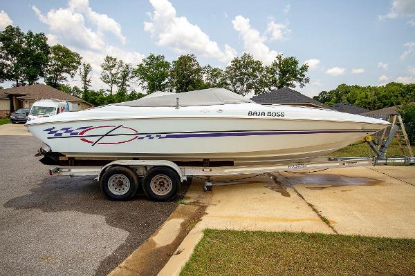 Baja Boss 272 1999 Baja Boss 272 boat on trailer, parked in driveway, with trees and houses in background.
