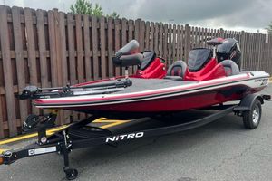 Nitro Z17 2026 Nitro Z17 boat in red on trailer, parked by wooden fence.