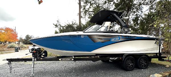 Tigé Z3 2017 Tigé Z3 boat on trailer, blue and white design, parked outdoors.