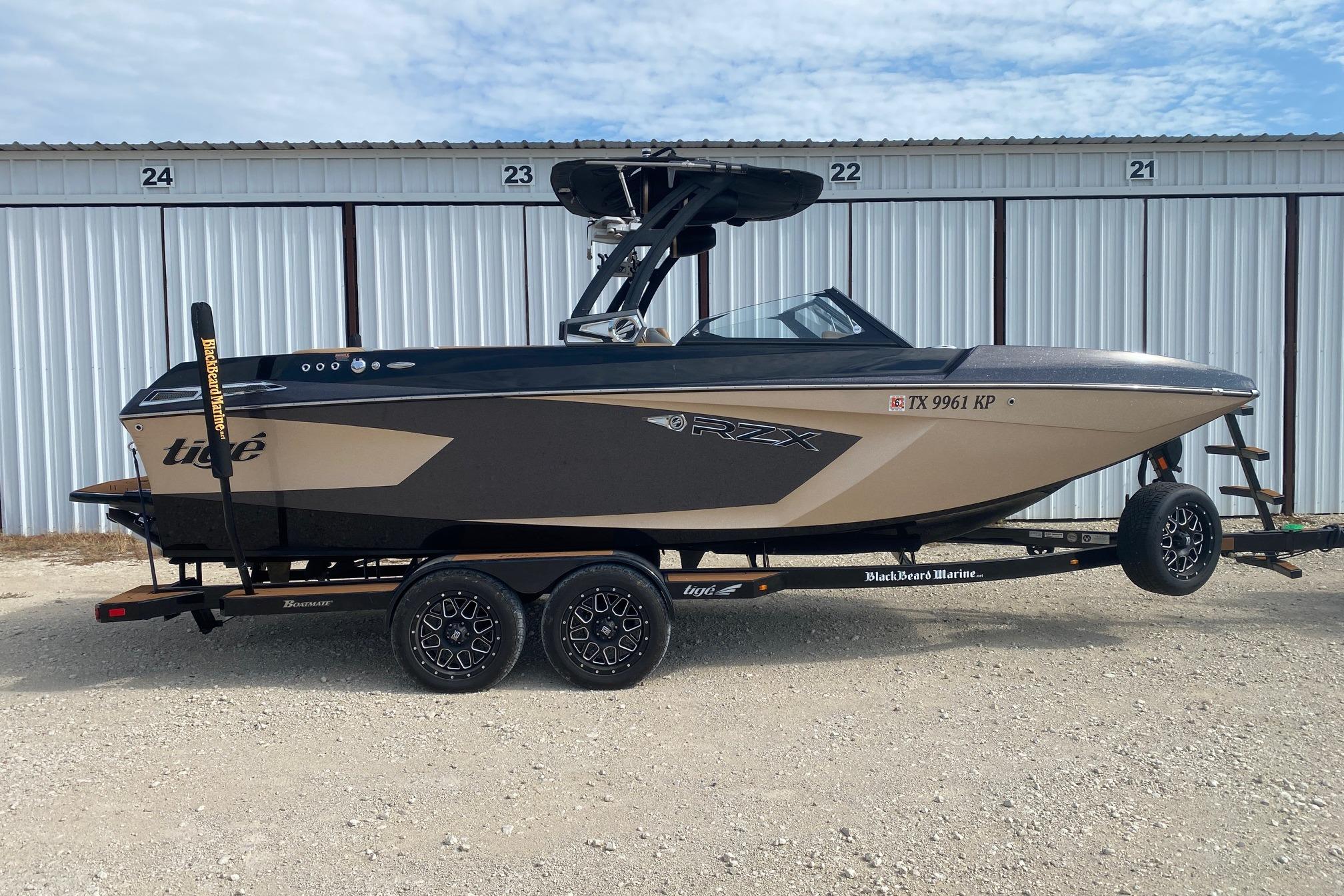 Tigé 23RZX 2021 Tigé 23RZX boat on trailer, parked in front of storage units.