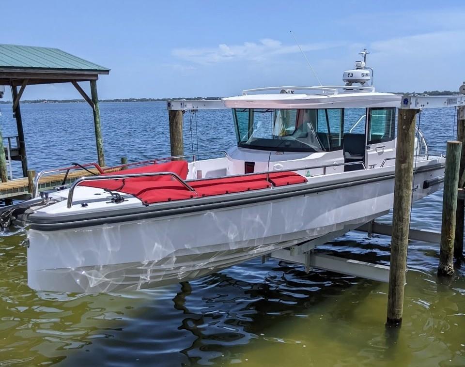 Axopar 28 CABIN 2022 Axopar 28 CABIN boat docked on a lift by the water.
