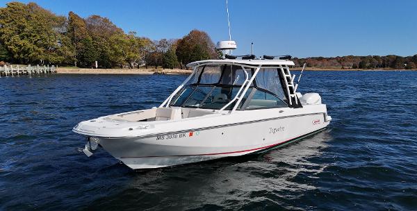 Boston Whaler 270 Vantage 2018 Boston Whaler 270 Vantage boat on calm water near a wooded shoreline.