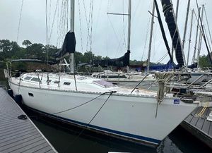 Catalina 400 1998 Catalina 400 sailboat docked at marina, white hull, black sails, overcast sky.