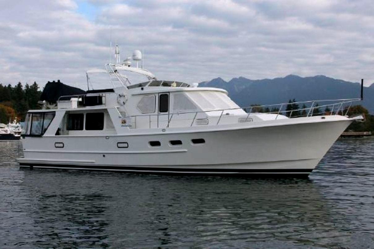 Custom Aluminum Pilothouse J Simpson Custom 1989 Aluminum Pilothouse J Simpson yacht on calm water with mountainous backdrop.