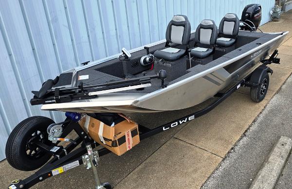 Lowe Skorpion Stick Steer 2025 Lowe Skorpion Stick Steer boat with three seats, on a trailer, parked by a blue wall.