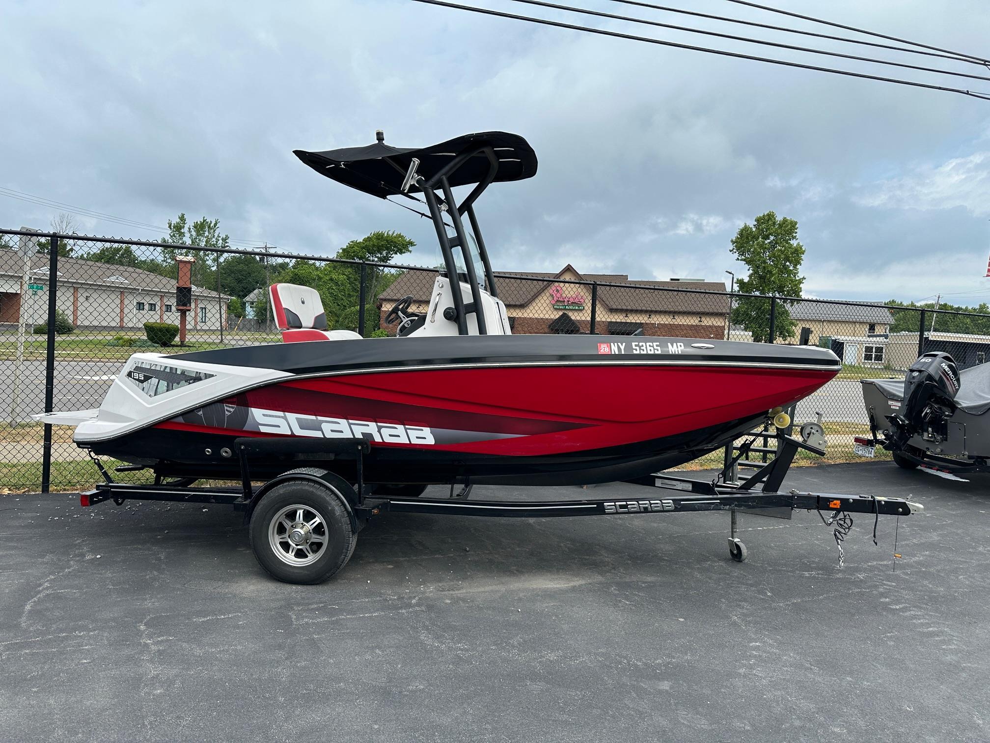 Scarab 195 Open ID 2018 Scarab 195 Open ID boat in red and black on a trailer, parked outdoors.