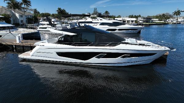 Sunseeker 65 Sport Yacht 2023 Sunseeker 65 Sport Yacht docked in a marina, surrounded by other luxury boats.