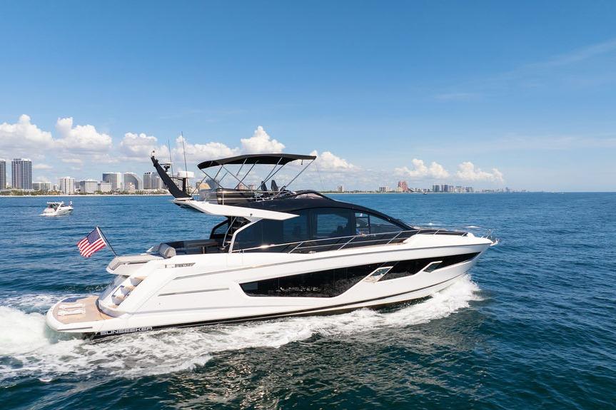 Sunseeker 65 Sport Yacht 2023 Sunseeker 65 Sport Yacht cruising on open water, city skyline in background.