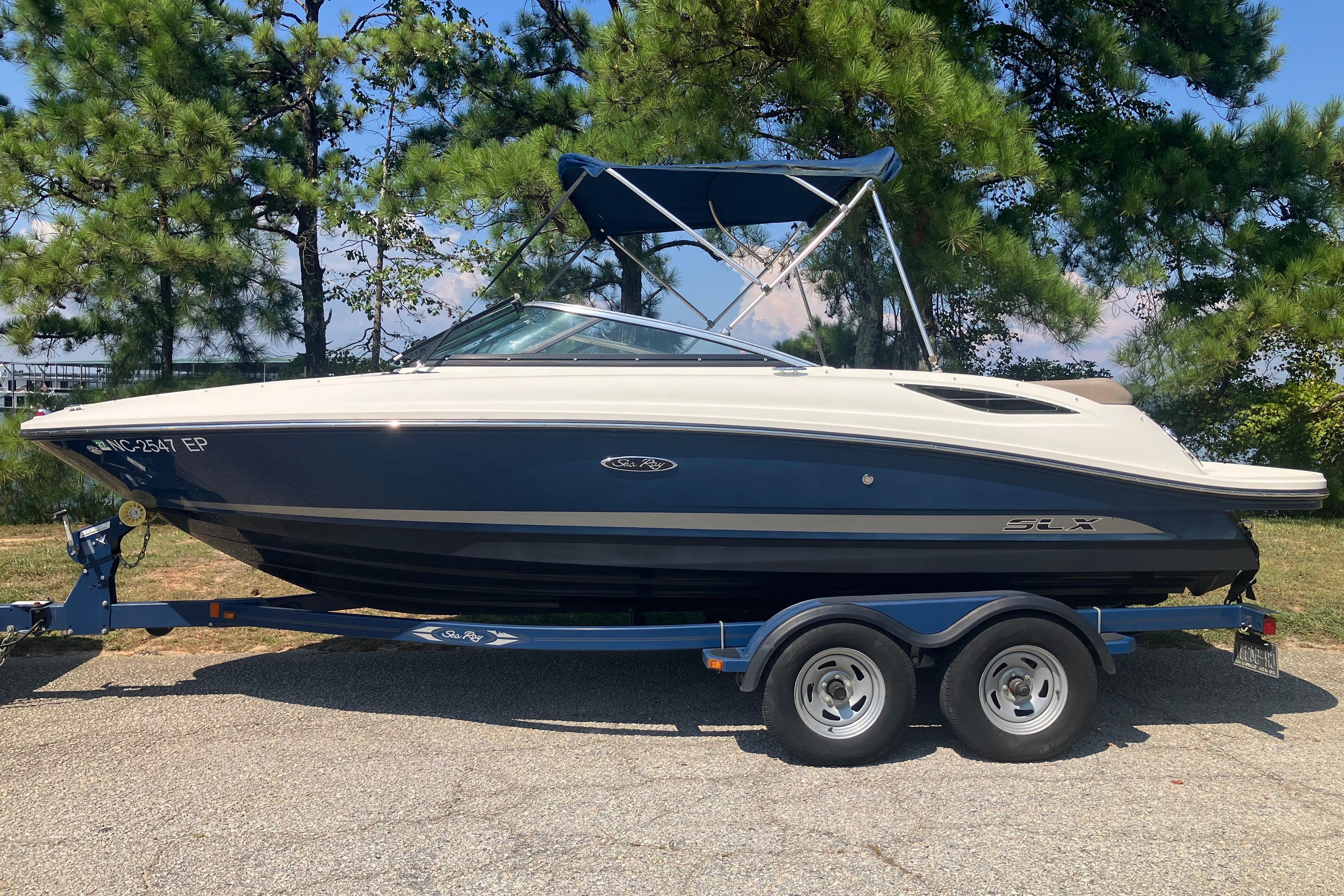 Sea Ray 210 SLX 2013 Sea Ray 210 SLX boat on trailer, parked outdoors near trees.