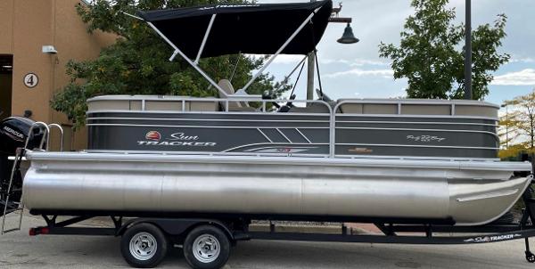 Sun Tracker Party Barge 22 DLX 2025 Sun Tracker Party Barge 22 DLX pontoon boat on trailer, parked outdoors.