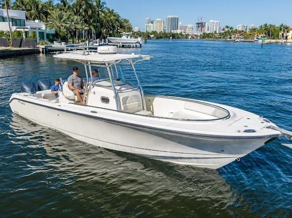 Edgewater 318CC 2010 Edgewater 318CC boat cruising on a sunny waterfront with city skyline.