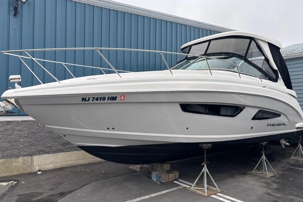 Regal 33 XO 2019 Regal 33 XO boat on stands, white hull, blue building background.