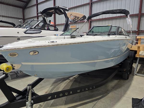 Four Winns H2 OB 2025 Four Winns H2 OB boat in showroom, light blue hull, on trailer.